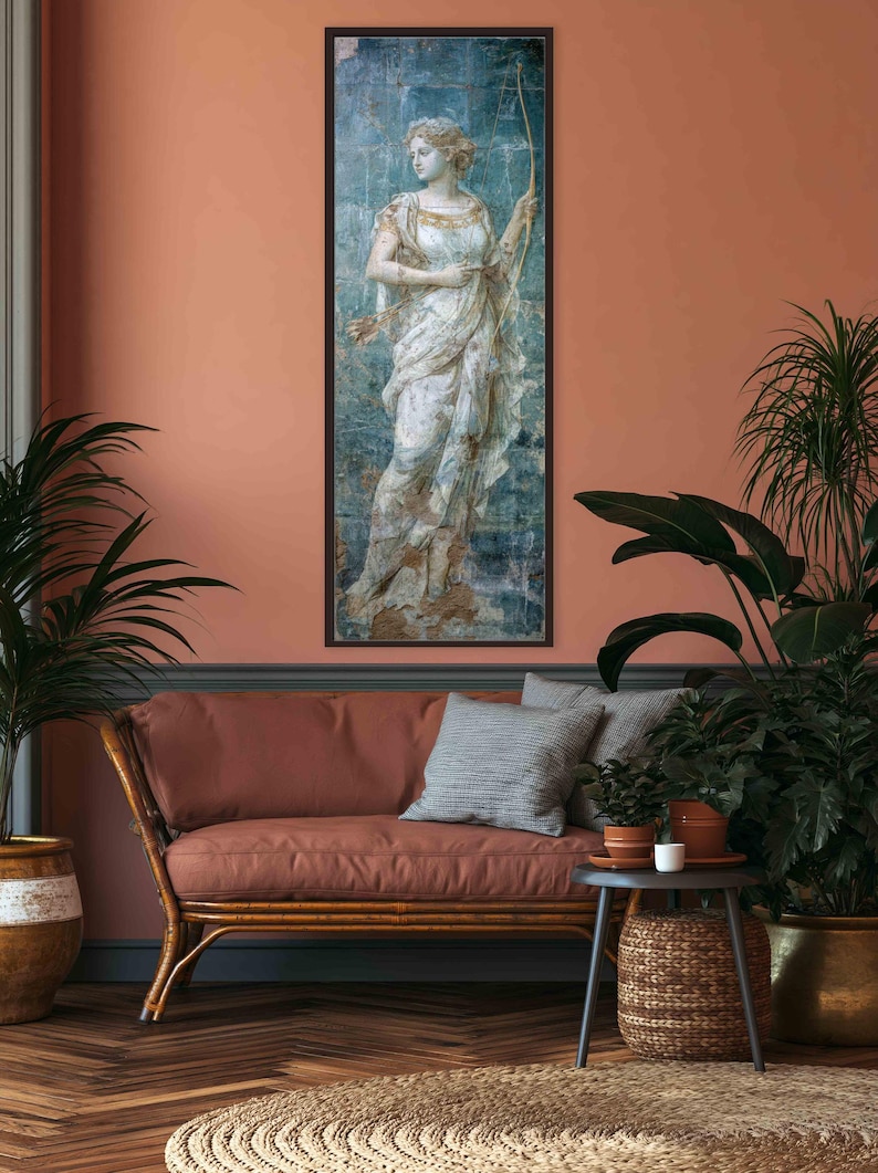 May include: A vertical rectangular framed wall art print featuring a classical figure in a flowing white draped garment, holding a long bow. The artwork has a weathered, distressed texture with blue and gold tones, set against a solid dark frame.