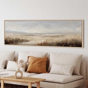 May include: A long, horizontal landscape painting in a light wood frame depicting a vast, open field with tall, dried grasses in shades of beige, tan, and dark brown under a soft, overcast sky with muted grey and white clouds.