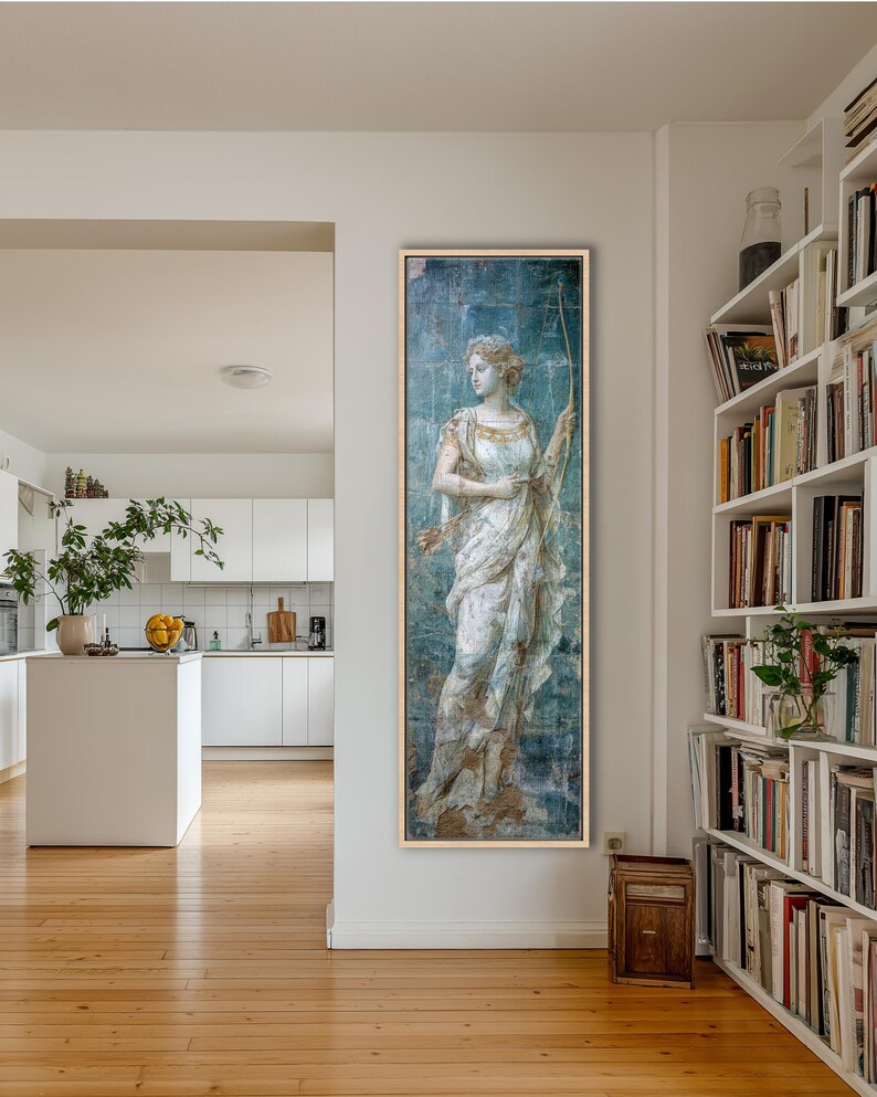 May include: A tall, rectangular framed wall art piece featuring a classical figure in a white draped garment holding a bow. The artwork has a weathered, distressed blue and gold finish with visible grid lines, presented in a light wood frame.
