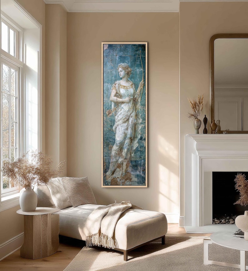 May include: A tall, rectangular framed wall art piece featuring a classical-style figure holding a bow, rendered in shades of blue, white, and gold. The artwork is displayed in a thin, light-colored wooden frame, showcasing a vertical composition.