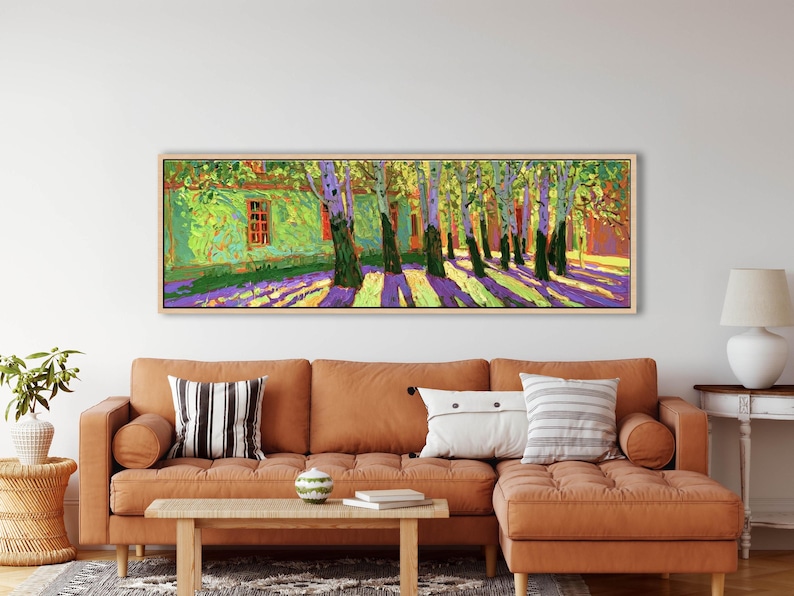 Puede incluir: Una pintura de paisaje panor&aacute;mico en un marco de madera clara que muestra un edificio verde vibrante con marcos de ventana rojos rodeado por una hilera de &aacute;rboles. El suelo est&aacute; cubierto de largas sombras p&uacute;rpuras y amarillas.