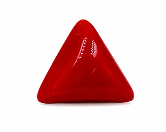 May include: A solid, vibrant red triangular object with a smooth, glossy finish. The piece features rounded corners and a slightly convex surface that reflects light, creating a bright white highlight near the top center of the triangular shape.