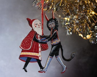 Wooden hanging Christmas ornament featuring Saint Nick dancing with the Christmas Krampus