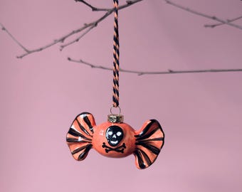 Boule d'Halloween en céramique représentant un bonbon empoisonné. Rayures orange et noires avec tête de mort. Fait main et peint à la main