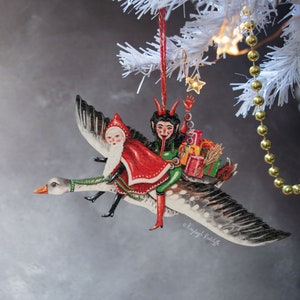 Weihnachtsanhänger mit Krampus und Weihnachtsmann auf einer fliegenden Gans. Retro Vintage-Stil festliche Dekoration, hergestellt in Großbritannien