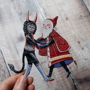 Wooden hanging Christmas ornament featuring Saint Nick dancing with the Christmas Krampus image 4