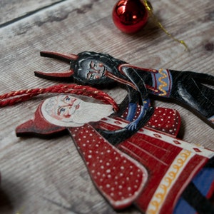 Wooden hanging Christmas ornament featuring Saint Nick dancing with the Christmas Krampus image 3