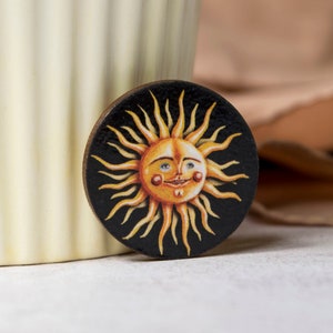 Sun badge/pin made from laser cut wood. Made in the UK. Featuring a quirky and vintage inspired celestial artwork