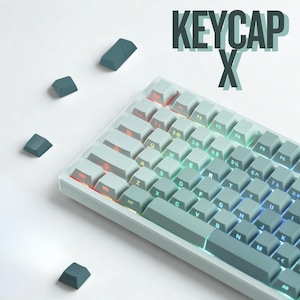 May include: A light gray mechanical keyboard with teal keycaps. The keyboard has illuminated keys with a gradient of colors. The text "KEYCAP X" is displayed above the keyboard. Several loose keycaps are scattered around the keyboard.