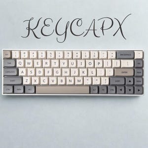 May include: A white and gray mechanical keyboard with beige keycaps. The keyboard has a compact layout with a variety of function keys and the text "KEYCAPX" in a script font above.