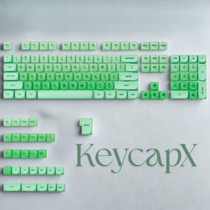 May include: A collection of mint green keyboard keycaps, including the main keyboard layout, number pad, and function keys. The keycaps are displayed on a white surface, with the brand name "KeycapX" in a matching green font.