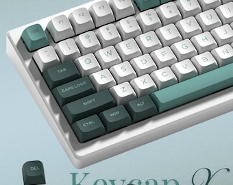 Op de afbeelding: Een witte en teal mechanische toetsenbord met witte keycaps en teal accenttoetsen. Het toetsenbord heeft een compacte indeling met diverse functietoetsen en een teal spatiebalk. De tekst "Keycap X" is onderaan zichtbaar.