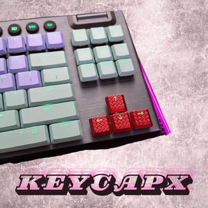 May include: A close-up of a mechanical keyboard with various colored keycaps. The keycaps are in shades of purple, teal, and red. The keyboard has a dark gray base with the text "KEYCAPX" in a pink and black font at the bottom.