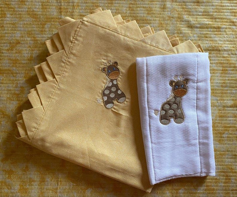 May include: Two baby blankets, one yellow with a giraffe design and one white with a giraffe design.