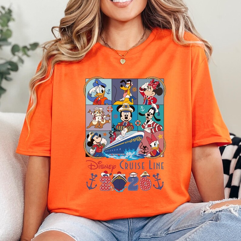Puede incluir: Camiseta naranja con un dise&ntilde;o colorido de personajes de Disney, incluyendo Mickey Mouse, Minnie Mouse, Donald Duck y Goofy, dispuestos en una cuadr&iacute;cula. El dise&ntilde;o incluye un crucero y el texto "Disney Cruise Line".