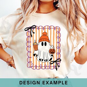 May include: Cream-colored t-shirt featuring a Halloween ghost illustration. The ghost wears an orange beanie and holds a pumpkin bucket and a drink. The design is framed with a purple scalloped border and orange and white stripes. Black bows are at the top and bottom.