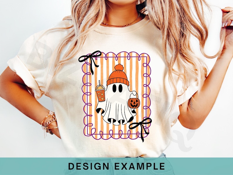 May include: Cream-colored t-shirt featuring a Halloween ghost illustration. The ghost wears an orange beanie and holds a pumpkin bucket and a drink. The design is framed with a purple scalloped border and orange and white stripes. Black bows are at the top and bottom.