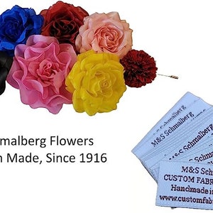 Peut inclure: Un assortiment de fleurs en tissu color&eacute;es, rouges, roses, bleues, jaunes et noires. Les fleurs sont regroup&eacute;es, avec une &eacute;pingle attach&eacute;e &agrave; l'une d'elles. L'image comprend &eacute;galement des &eacute;tiquettes indiquant "M&S Schmalberg Flowers, American Made, Since 1916."