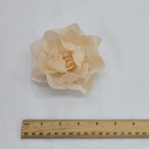 May include: A large, peach-colored fabric flower with multiple layers of petals. The flower is approximately 2 inches in diameter.
