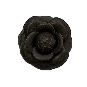 May include: A dark brown leather flower brooch with a textured surface.