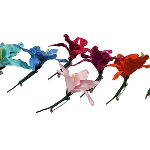 May include: Assortment of eight fabric flower brooches in various colors, including turquoise, blue, pink, red, orange, and yellow. Each flower has a green stem and a silver pin.