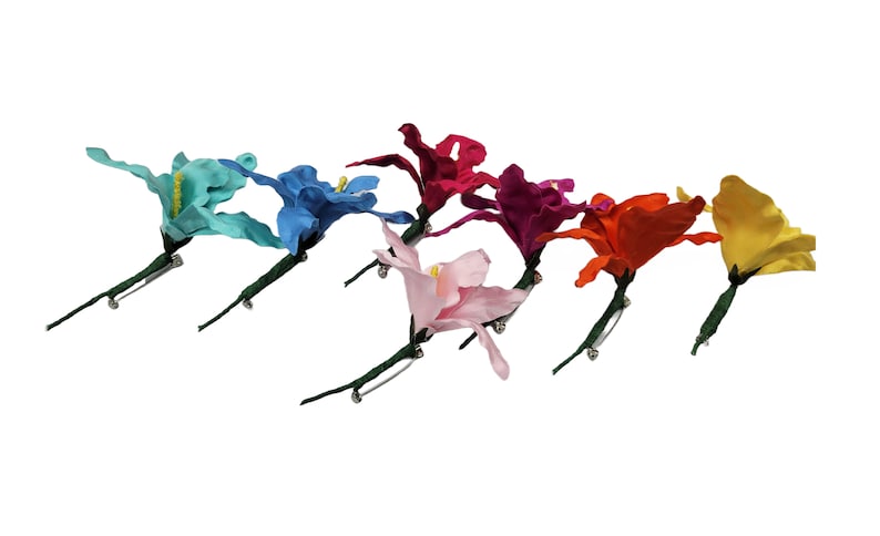 May include: Assortment of eight fabric flower brooches in various colors, including turquoise, blue, pink, red, orange, and yellow. Each flower has a green stem and a silver pin.