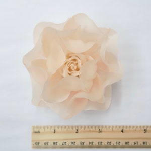 May include: A large, peach-colored fabric rose with a ruffled texture. The rose is approximately 4 inches in diameter.