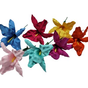 May include: A bouquet of seven artificial silk flowers in various colors, including pink, blue, yellow, red, and orange. The flowers are arranged in a cluster and have a realistic appearance.