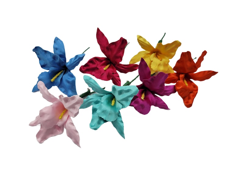 May include: A bouquet of seven artificial silk flowers in various colors, including pink, blue, yellow, red, and orange. The flowers are arranged in a cluster and have a realistic appearance.