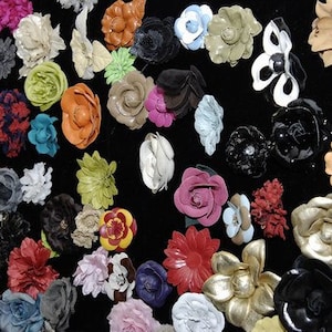 Peut inclure: Une collection de d&eacute;corations florales artificielles color&eacute;es de diff&eacute;rentes formes et tailles. Les fleurs sont dans des tons de rose, rouge, orange, bleu, vert et blanc, dispos&eacute;es sur un fond noir. Certaines fleurs ont plusieurs couches.