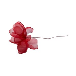 Può includere: Un singolo fiore di tessuto rosso intenso con petali delicati e traslucidi. Il fiore ha uno stelo di filo metallico che si estende verso destra. Il fiore è posto su uno sfondo bianco.