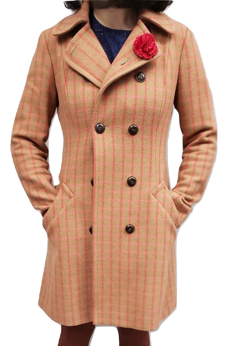 May include: A double-breasted, long-sleeved coat with a pink and beige plaid pattern. The coat has a collar and pockets. A red flower pin is on the lapel.