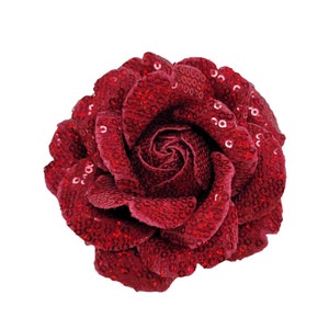 May include: A large, red rose made of fabric covered in sequins. The rose is a decorative item and is perfect for adding a touch of elegance to any room.