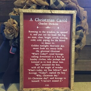 Peut inclure: Une pancarte en bois rouge avec du texte blanc qui dit "A Christmas Carol" de Charles Dickens. Le texte continue avec un extrait du livre, d&eacute;crivant une sc&egrave;ne d'un matin de No&euml;l lumineux et froid.