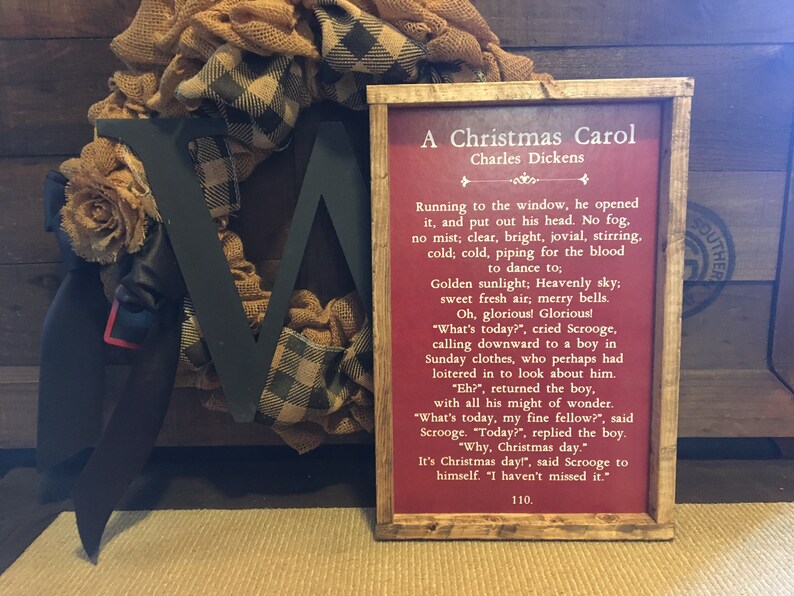 Peut inclure: Une impression encadr&eacute;e avec un fond rouge et du texte blanc. Le texte est un extrait de "Un chant de No&euml;l" de Charles Dickens. Le cadre est en bois avec une finition rustique.
