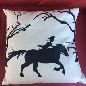 May include: A white pillow with a black silhouette of a person riding a horse through a forest. The pillow has a linen texture.