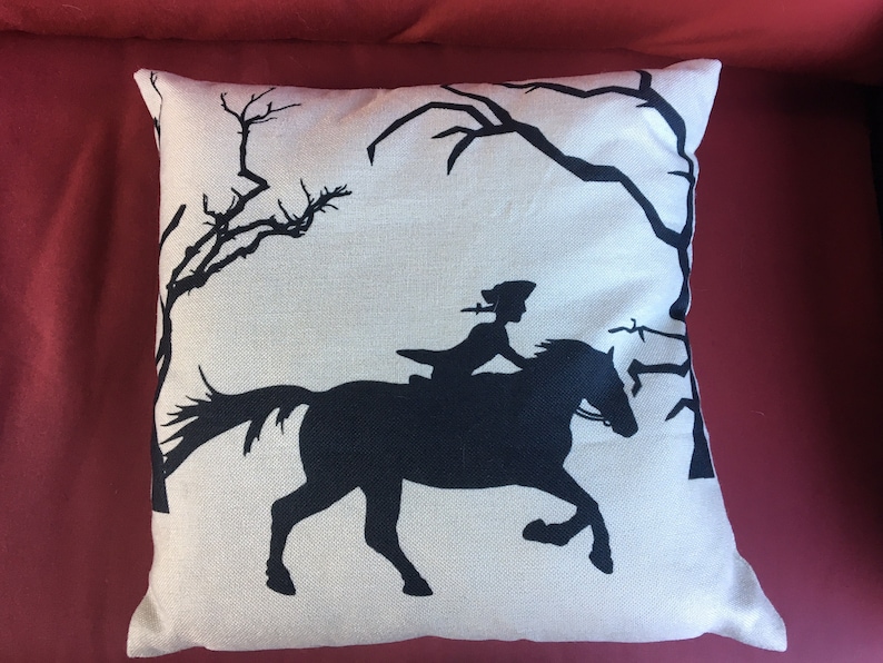 May include: A white pillow with a black silhouette of a person riding a horse through a forest. The pillow has a linen texture.