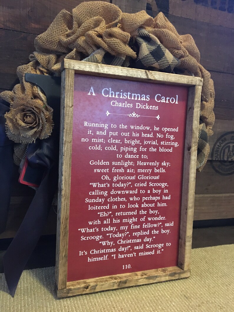 Peut inclure: Une pancarte en bois rouge avec une bordure blanche et du texte blanc. La pancarte indique "A Christmas Carol" de Charles Dickens. Le texte se poursuit avec un extrait du livre, d&eacute;crivant un matin de No&euml;l lumineux et froid.