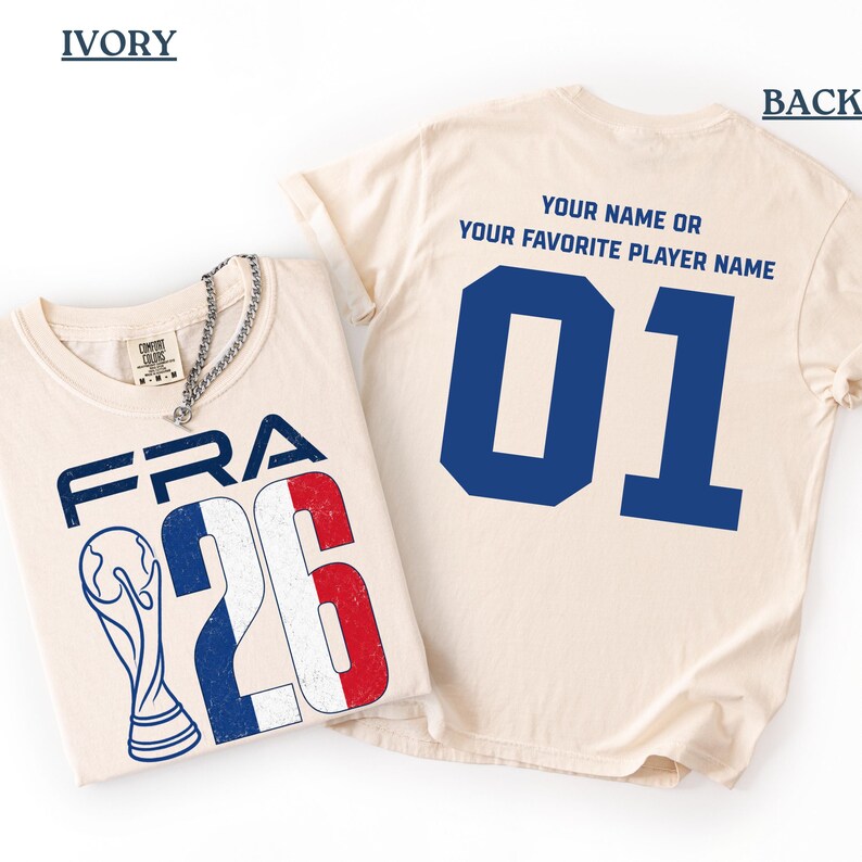 Puede incluir: Camisetas color marfil con dise&ntilde;os franceses. Una muestra "FRA 26" con un trofeo y los colores de la bandera francesa. La otra tiene un gran "01" azul en la espalda, con el texto "YOUR NAME OR YOUR FAVORITE PLAYER NAME."