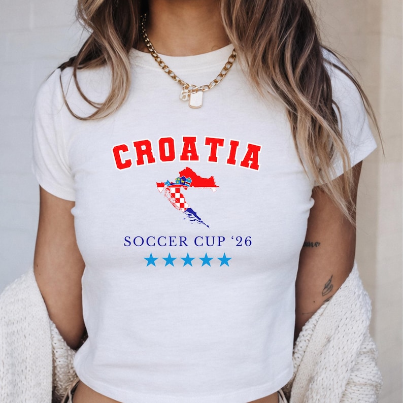 May include: White t-shirt with the word "CROATIA" in red block letters above a map of Croatia in red, white, and blue. Below the map, the text reads "SOCCER CUP '26" with five blue stars.
