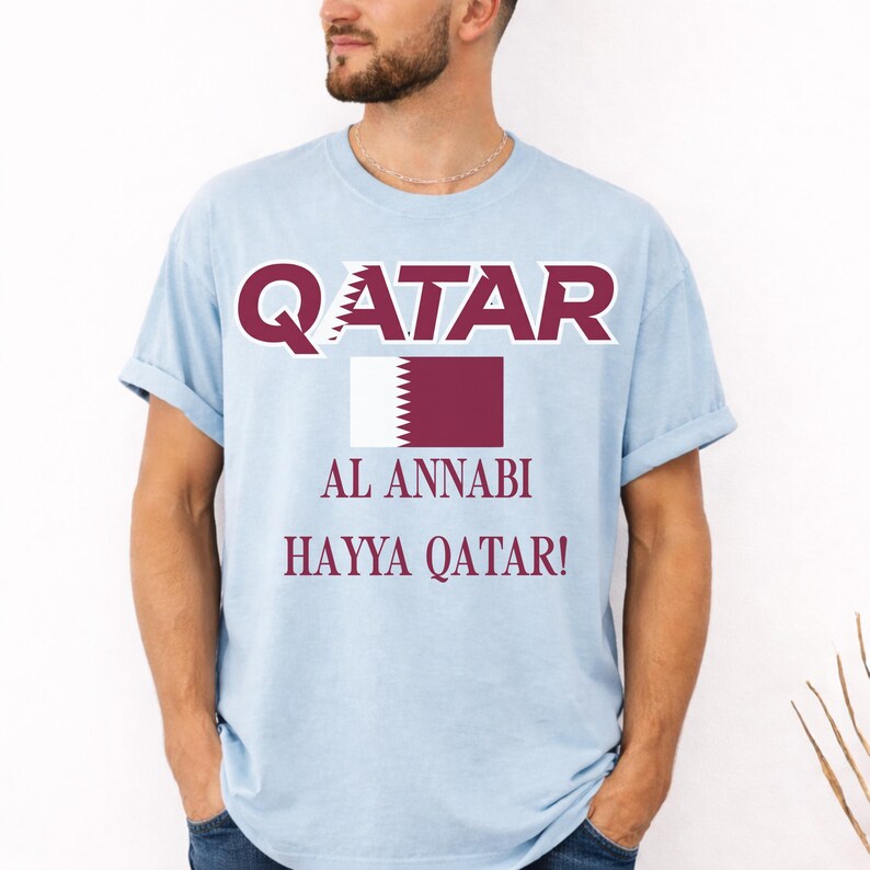 Chambray T-shirt showing a vibrant Qatar soccer flag graphic and Hayya Qatar chant print.