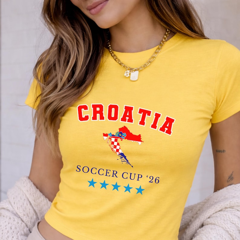 A vibrant yellow version of the Croatia soccer tee worn by a model. The blue "SOCCER CUP '26" text provides a bold contrast against the sunny fabric in warm outdoor light.