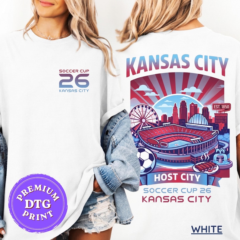 A blonde model wearing an oversized white t-shirt with a "Soccer Cup 26 Kansas City" chest logo and a large, colorful back graphic featuring the KC skyline, GEHA Field stadium, and a plate of BBQ.