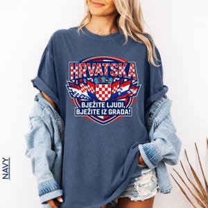 Navy blue oversized graphic tee showcasing Croatia national team colors and sports banner design, styled with a denim jacket on a smiling female model.