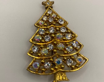 May include: A gold-toned Christmas tree brooch with clear and iridescent rhinestones.