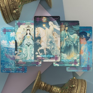 May include: Five rectangular tarot cards featuring blue and white illustrations of figures and cups, labeled Ace of Cups, Queen of Cups, Knight of Cups, King of Cups, and Page of Cups. The cards are arranged in a fan shape with ornate gold metal objects.