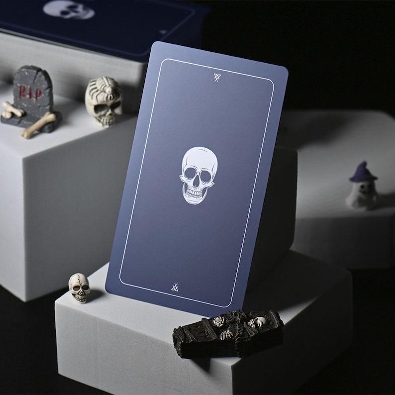 May include: A blue playing card with a white skull illustration and the symbol 'X' in the top and bottom corners.