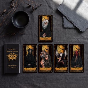 May include: A Persona Obscura tarot deck featuring a black guidebook with gold text and five rectangular cards. The cards display dark, detailed illustrations titled The Moon, The High Priestess, Strength, Temperance, and The Devil in gold banners.