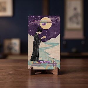 May include: A rectangular tarot card titled Temperance with the Roman numeral XIV, featuring an illustration of a figure in a black robe pouring water from a golden cup into a winding blue river under a large yellow moon in a dark purple starry sky.