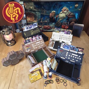 May include: A collection of tabletop gaming accessories, including player boards, card holders, dice, and tokens. The boards are in various colors, with slots for cards and dice. A decorative lantern and a hexagonal tile set are also present. The background features a digital painting.
